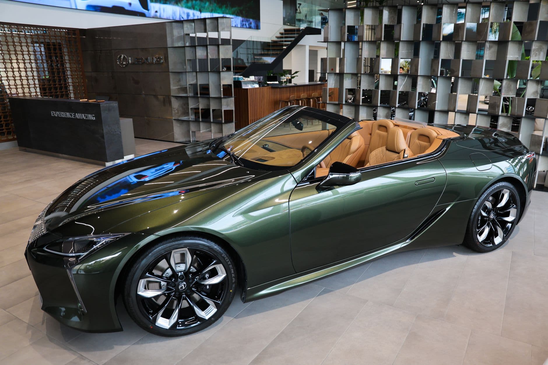 Luxury green convertible car displayed in an elegant showroom setting.