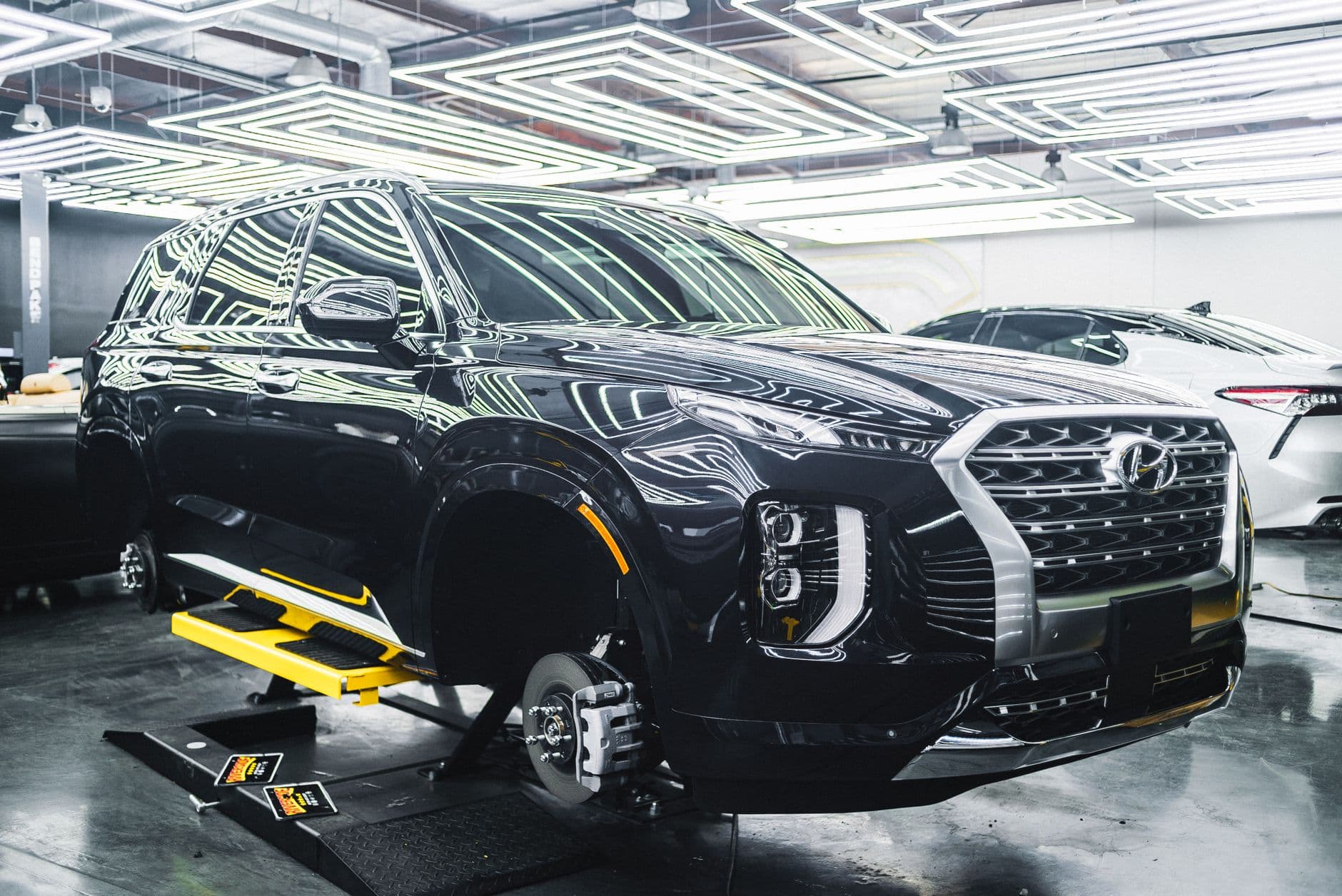 A Hyundai Palisade luxury SUV displayed in a sleek, modern garage under stylish lighting.