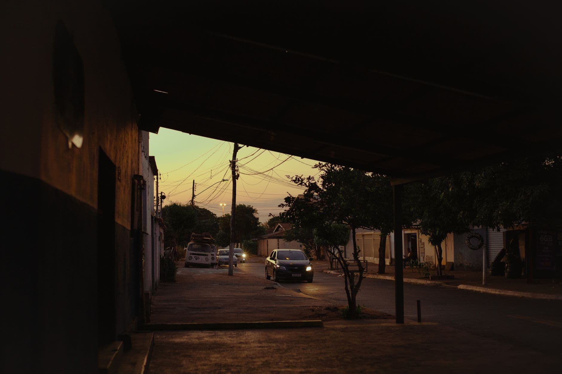 A quiet city street under a bridge at dusk with cars passing by, captured in an urban setting.