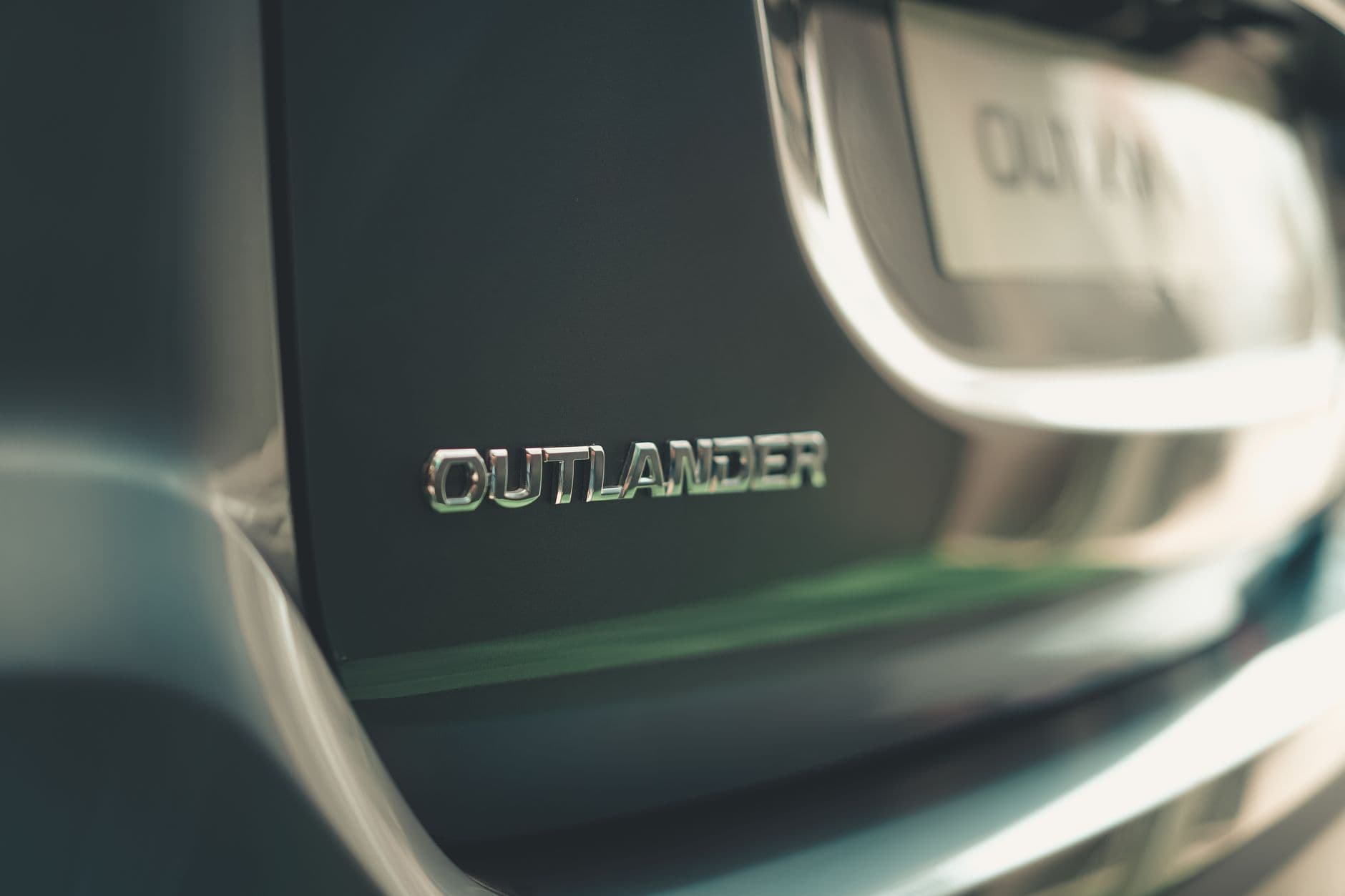 Detailed shot of Mitsubishi Outlander emblem on car rear, showcasing brand identity.